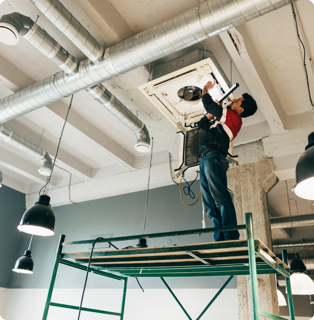 Worker on scaffold fixing HVAC system