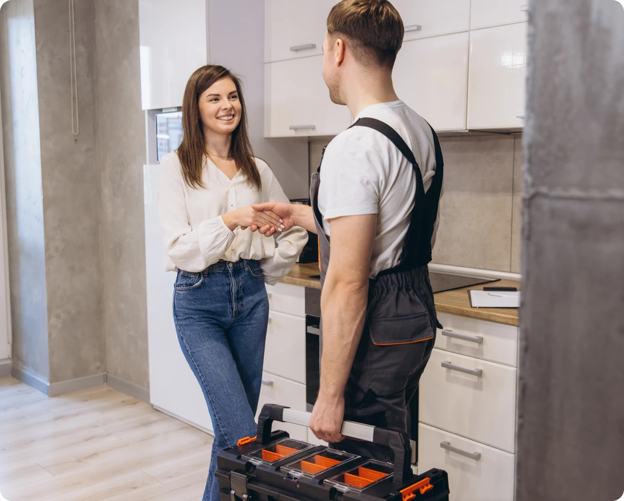 Smiling woman with repairman in kitchen