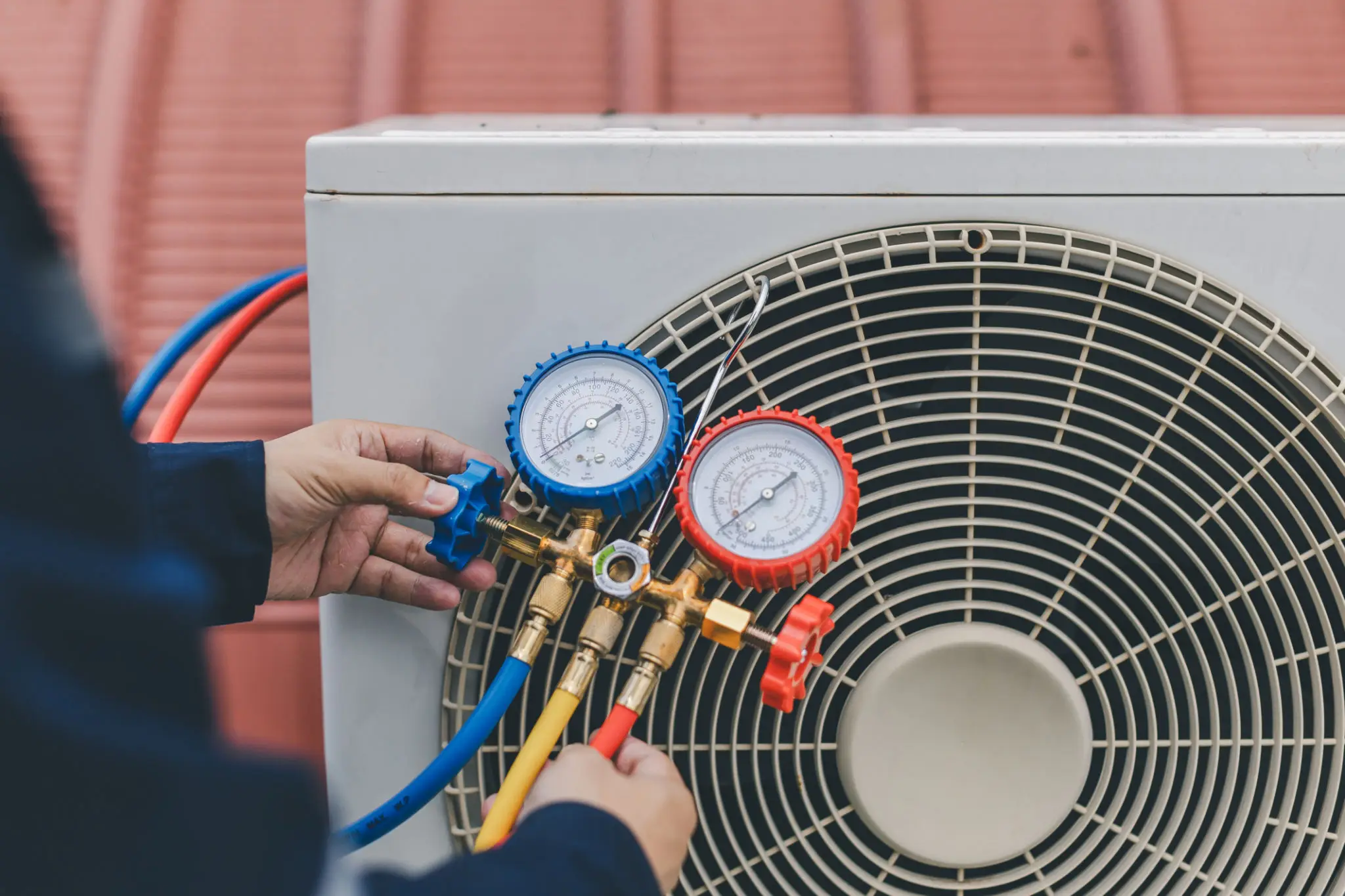 Technician using gauges to check an air conditioner's pressure.